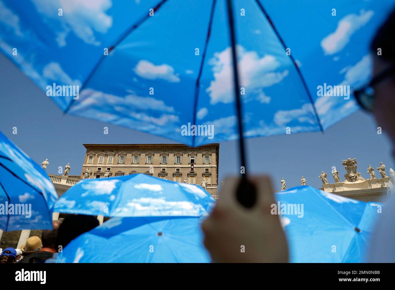 Faithful use their umbrellas to shelter from the sun as they listen to Pope Francis' message