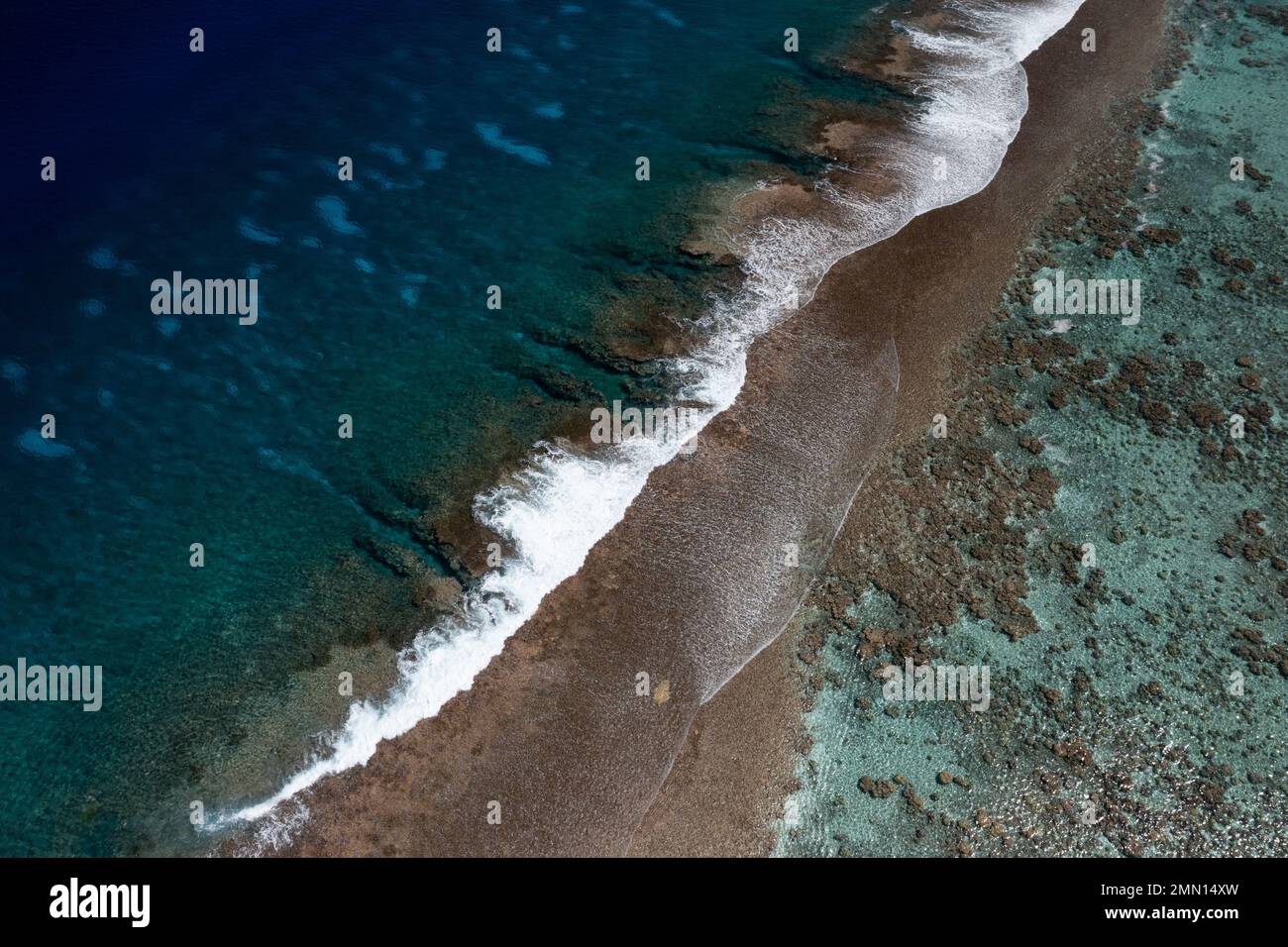 Waves crashing on a beautiful pristine coral reef in Tahaa, French Polynesia, with a drone Stock Photo