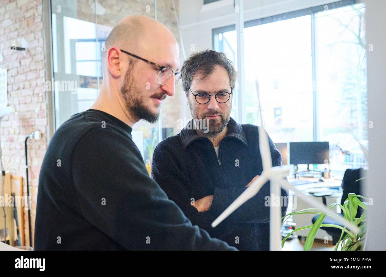 Berlin, Germany. 27th Jan, 2023. Daniel Deppe (l), project engineer for wind energy and environmental planner, and Elias Brunken, project engineer for wind energy and renewable energies, look at wind turbine models in the office of the company Teut Windprojekte. (to dpa 'Turbo for LNG, brake for wind? Why the energy turnaround is lame') Credit: Annette Riedl/dpa/Alamy Live News Stock Photo