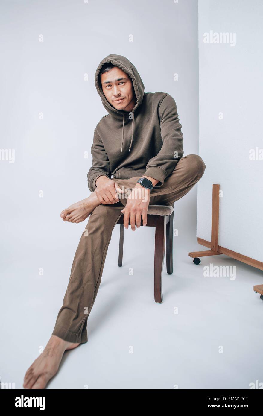 A young Asian man in a hoodie sitting on a white background Stock Photo ...