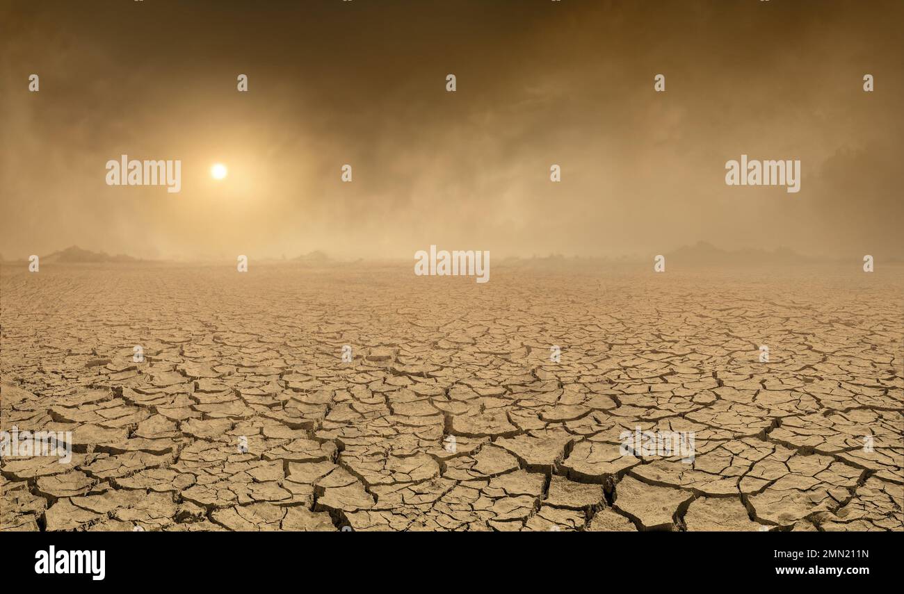 Panorama of arid barren land with cracked soil and sun barely visible through the approaching sand storm. Ecology problems concept Stock Photo