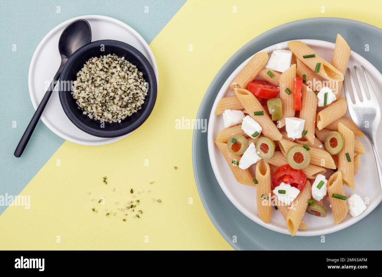 Red lentil penne salad with hempseeds on duo colored background Stock Photo