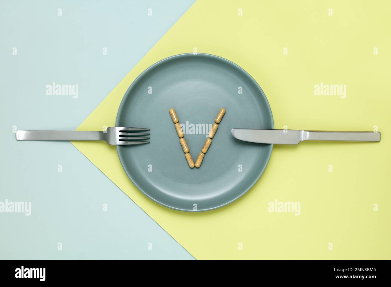 Vitamin capsules arrange in a v on blue green dinner plate Stock Photo