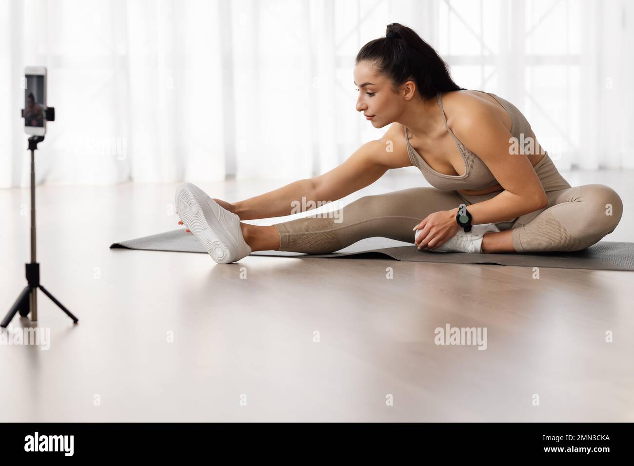 Young woman yoga instructor broadcasting while strecthing at home Stock Photo