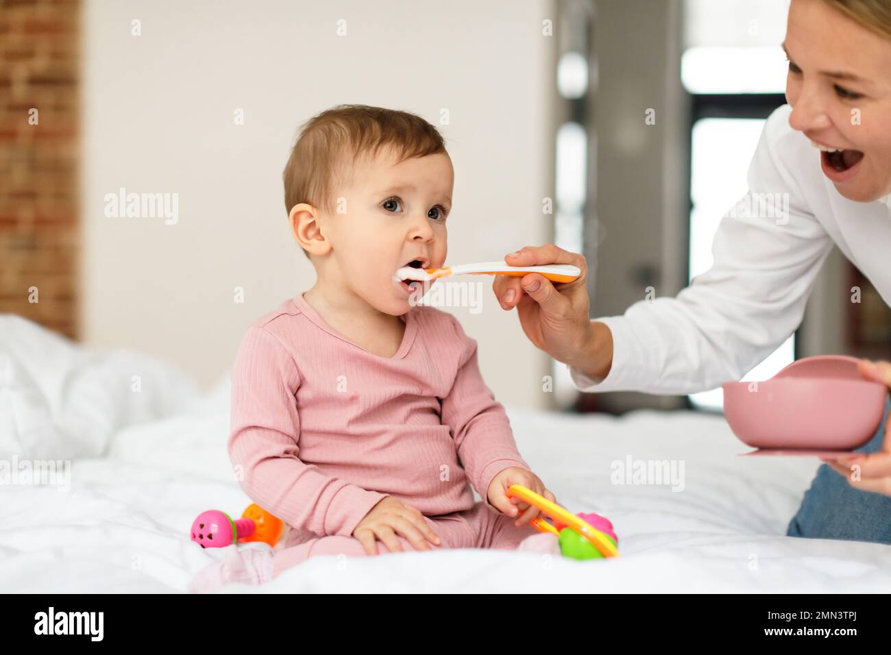 Breakfast for kid. Mother feeding her adorable baby daughter with