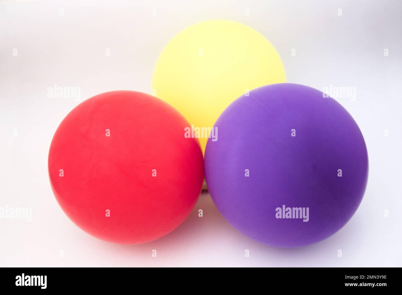 Three inflated balloons of the colors red, yellow and purple represent the republican flag in Spain on a neutral background Stock Photo