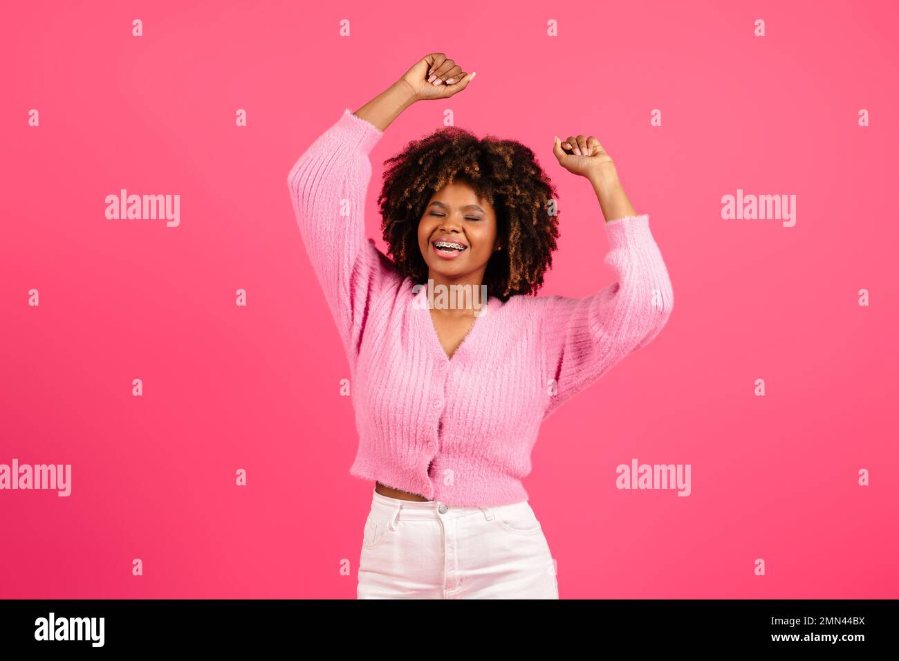 Cheerful pretty young african american curly woman in casual with braces dancing, enjoying music Stock Photo