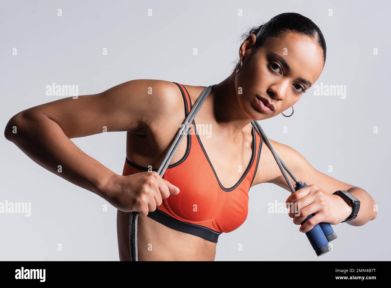brunette african american sportswoman in red sports bra holding skipping  rope isolated on grey Stock Photo - Alamy