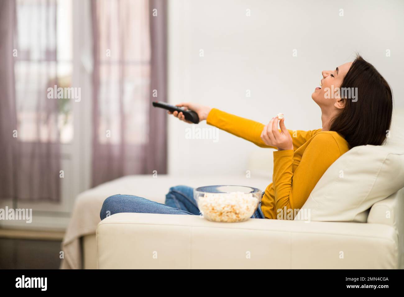 Happy brunette woman enjoying TV show, home interior Stock Photo