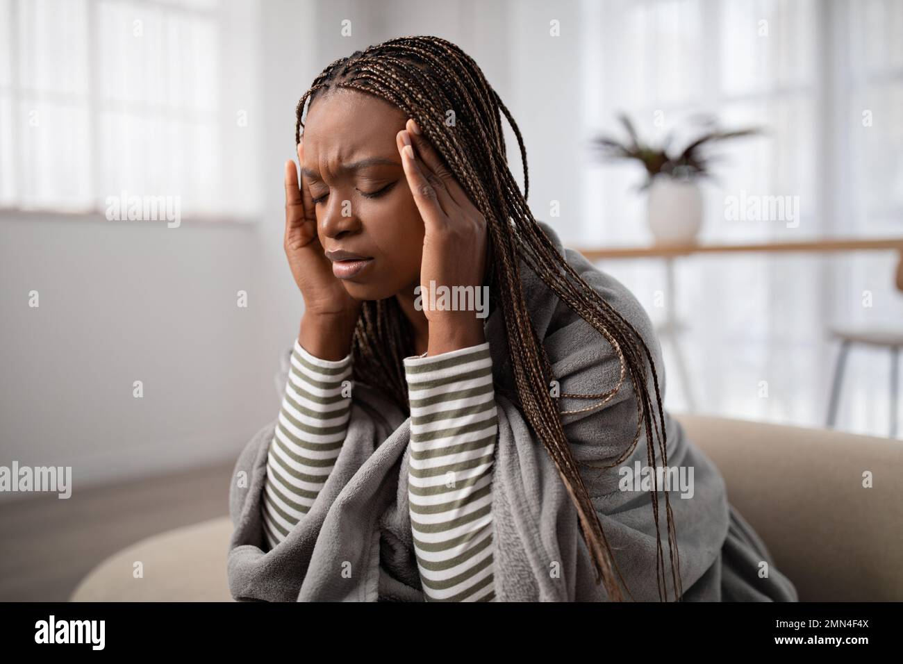 Tired young black woman suffering from headache, home interior Stock Photo