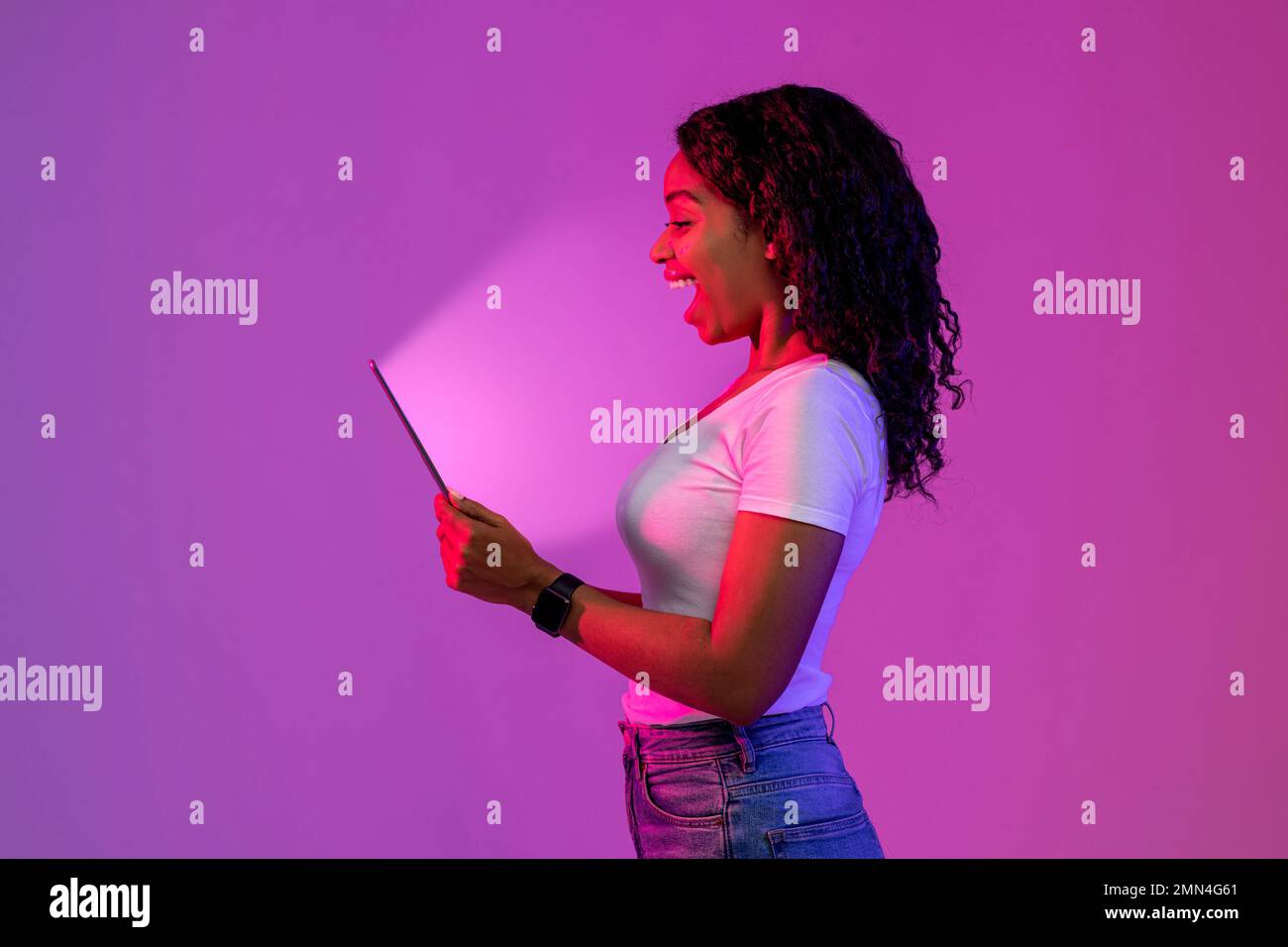 Surprised Black Woman Looking At Digital Tablet With Glowing Screen Stock Photo
