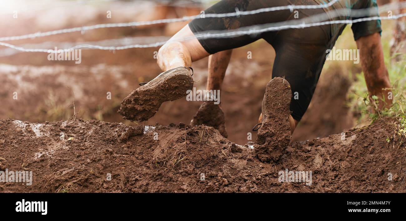 Mud race runners.Crawling,passing under a barbed wire obstacles during ...