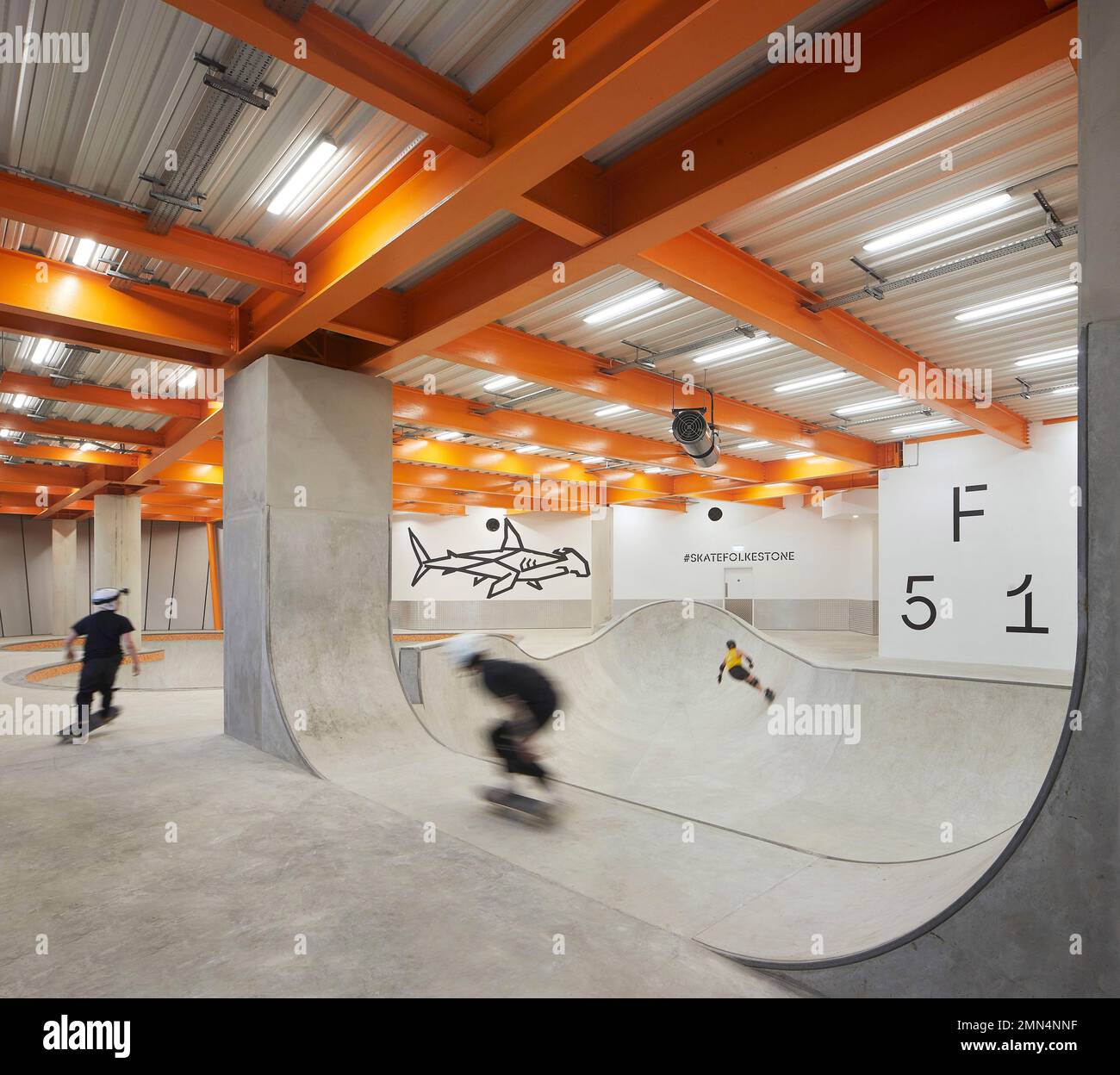 Inside of concrete skate bowl - youngsters practicing. F51 Skatepark, Folkestone, United Kingdom. Architect: Hollaway Studio, 2022. Stock Photo
