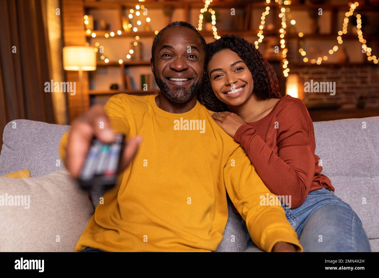 Portrait of loving black couple watching TV at home Stock Photo - Alamy