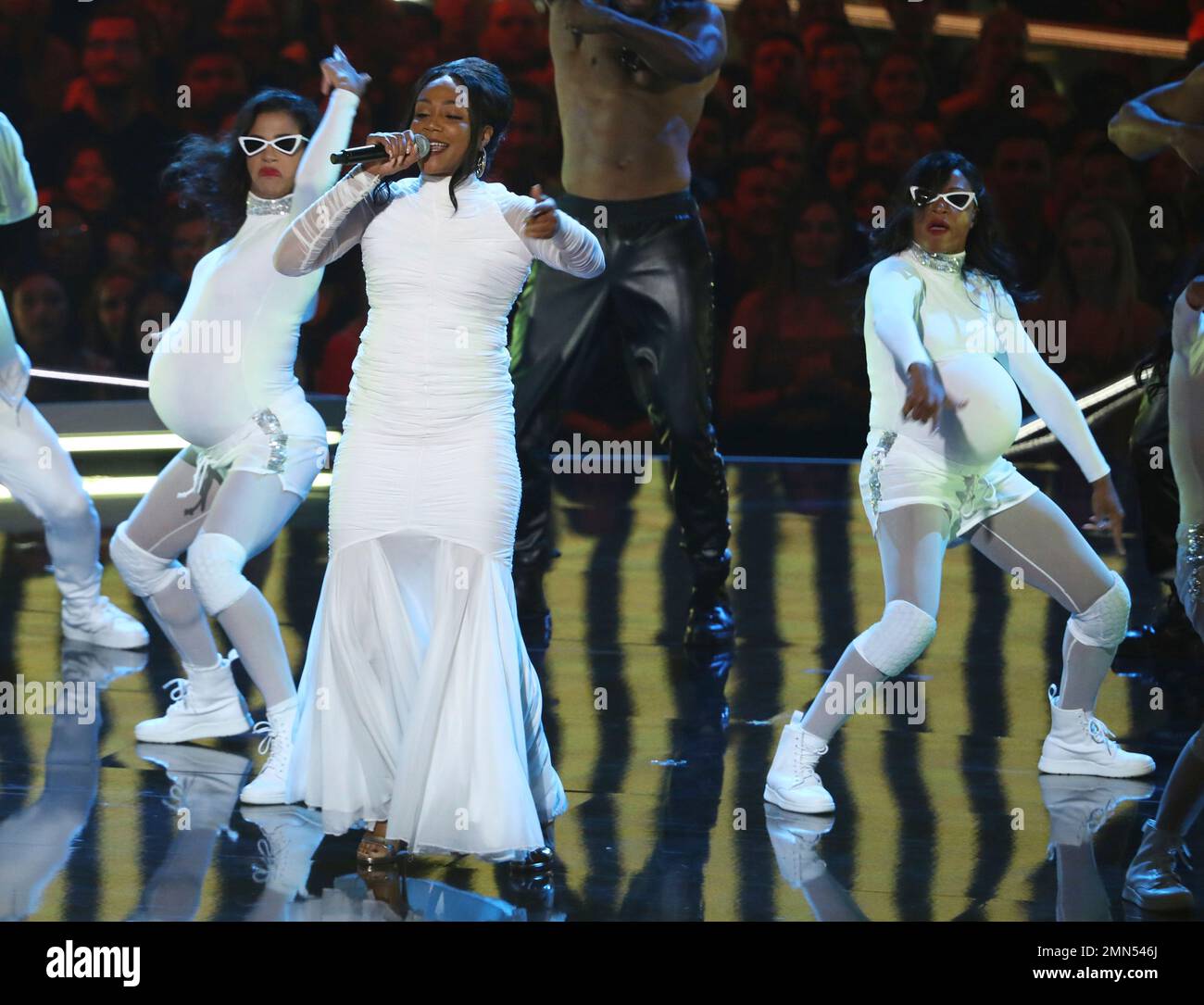 Tiffany Haddish, center, imitates a pregnant Cardi B as she performs a