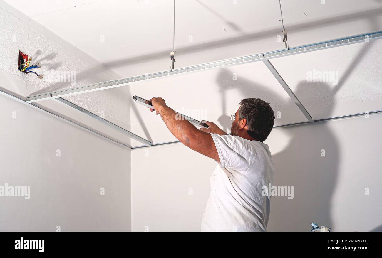 Construction worker assemble a suspended ceiling with drywall an. D