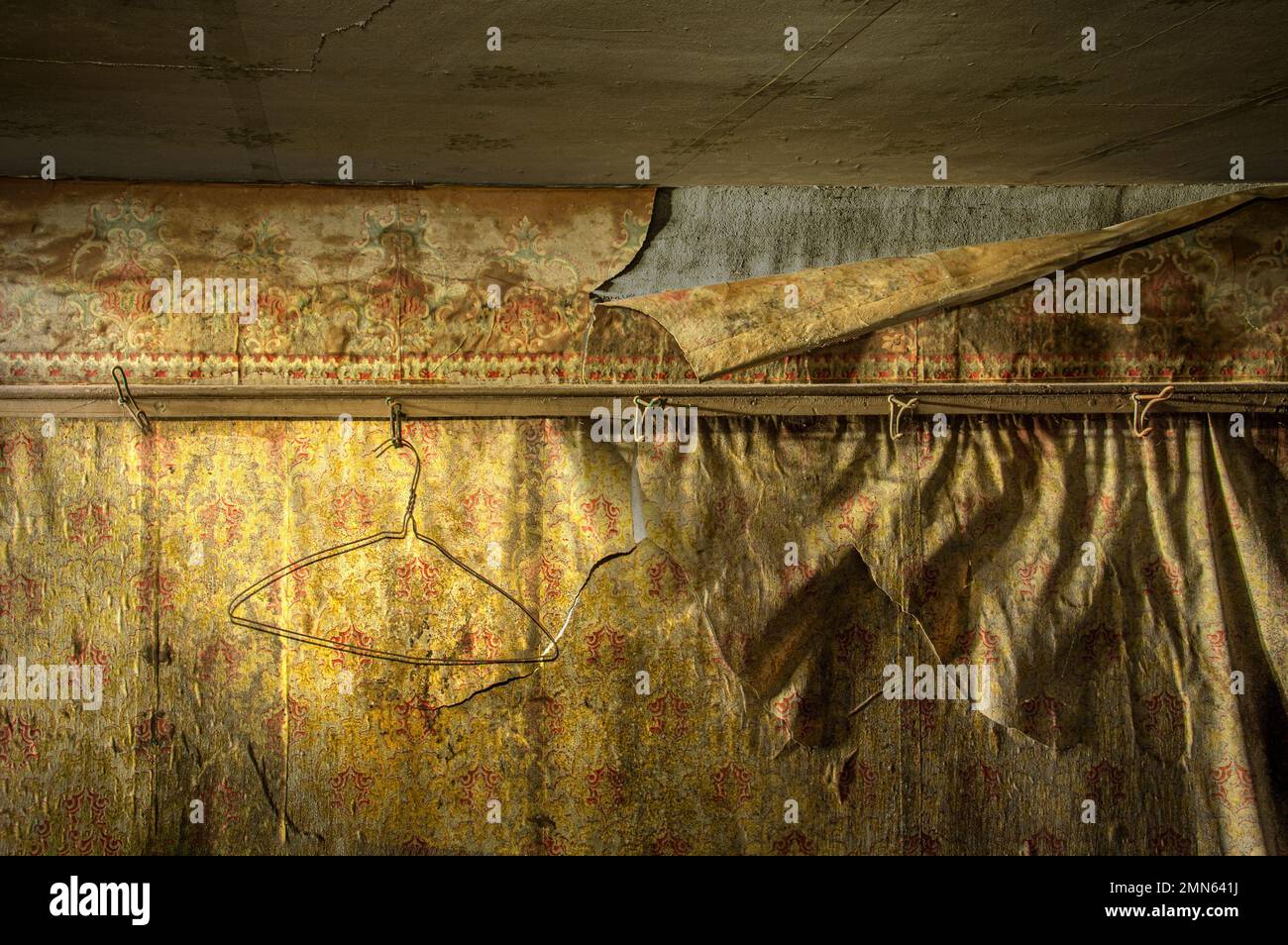 Rusty metal clothes hanger with peeling wallpaper inside abandoned home, Pennsylvania, USA Stock Photo