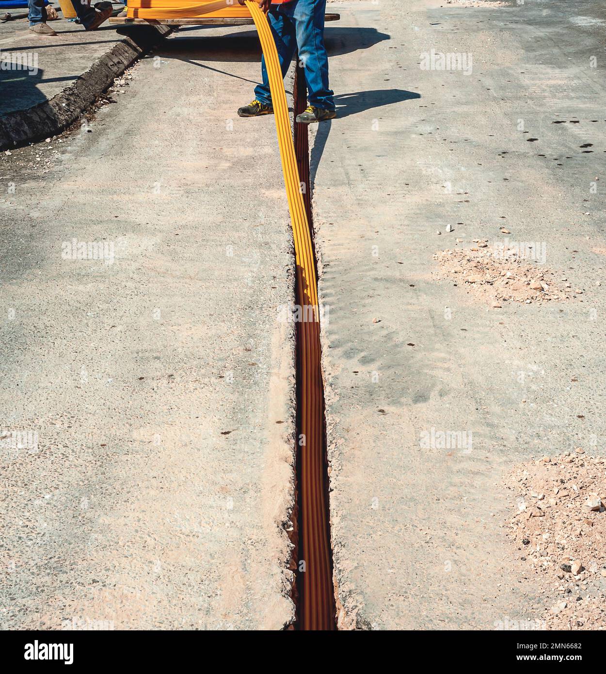 Worker inserts fiber optic cables buried in a micro trench Stock Photo