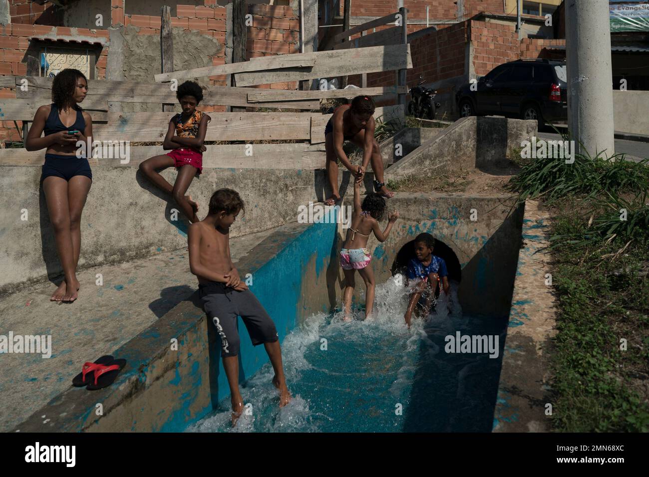 Children play in a drainage canal that they partially blocked to turn ...