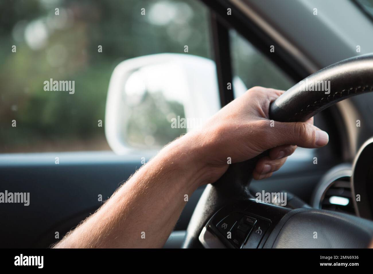 The driver's hand on the steering wheel of the car. Driving, traffic