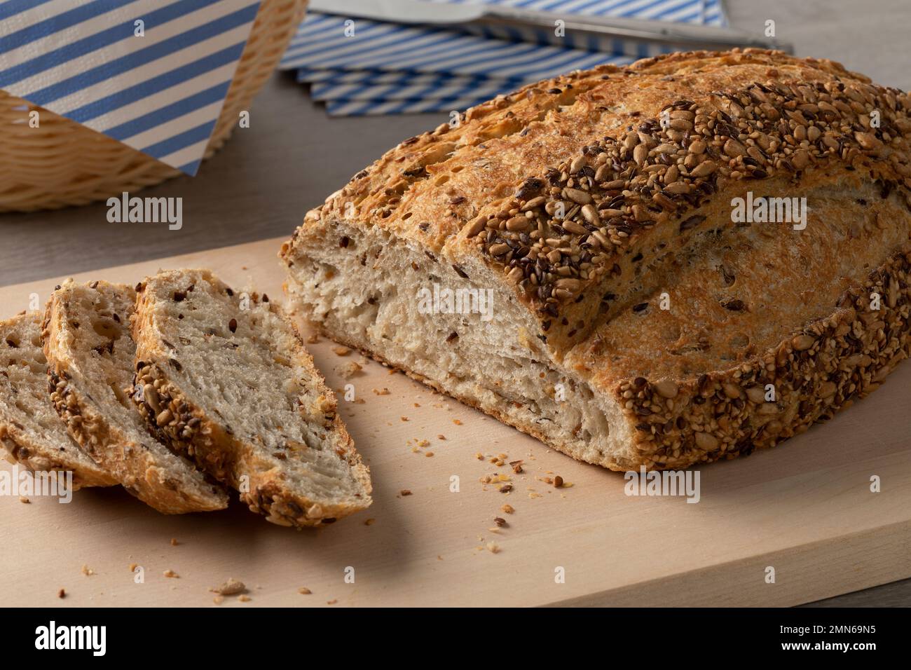 Fresh loaf and slices of country bread,  pain de campagne, and seeds close up on a cutting board Stock Photo