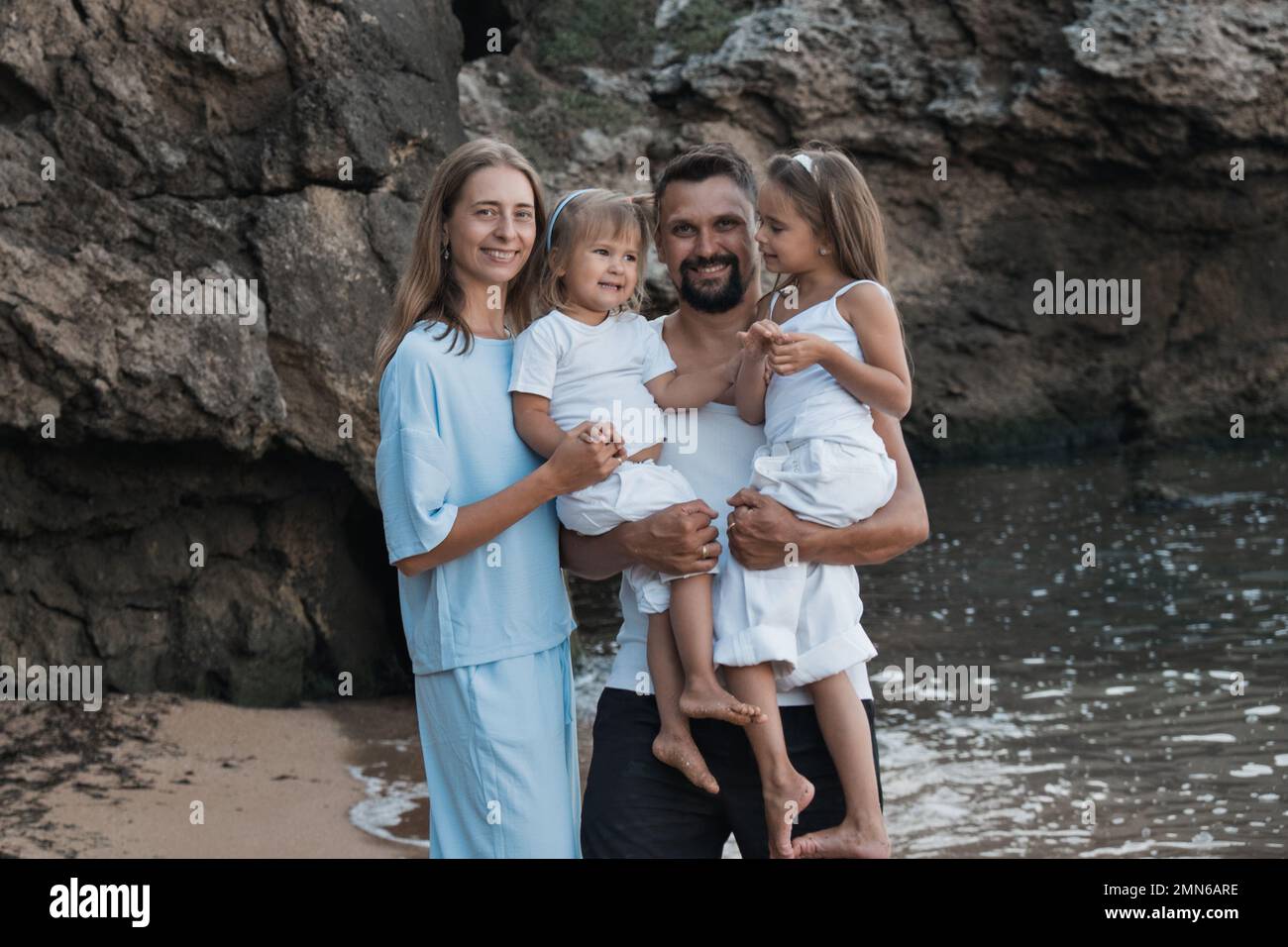 Happy smiling parents mom and dad hug their children at the sea, near ...