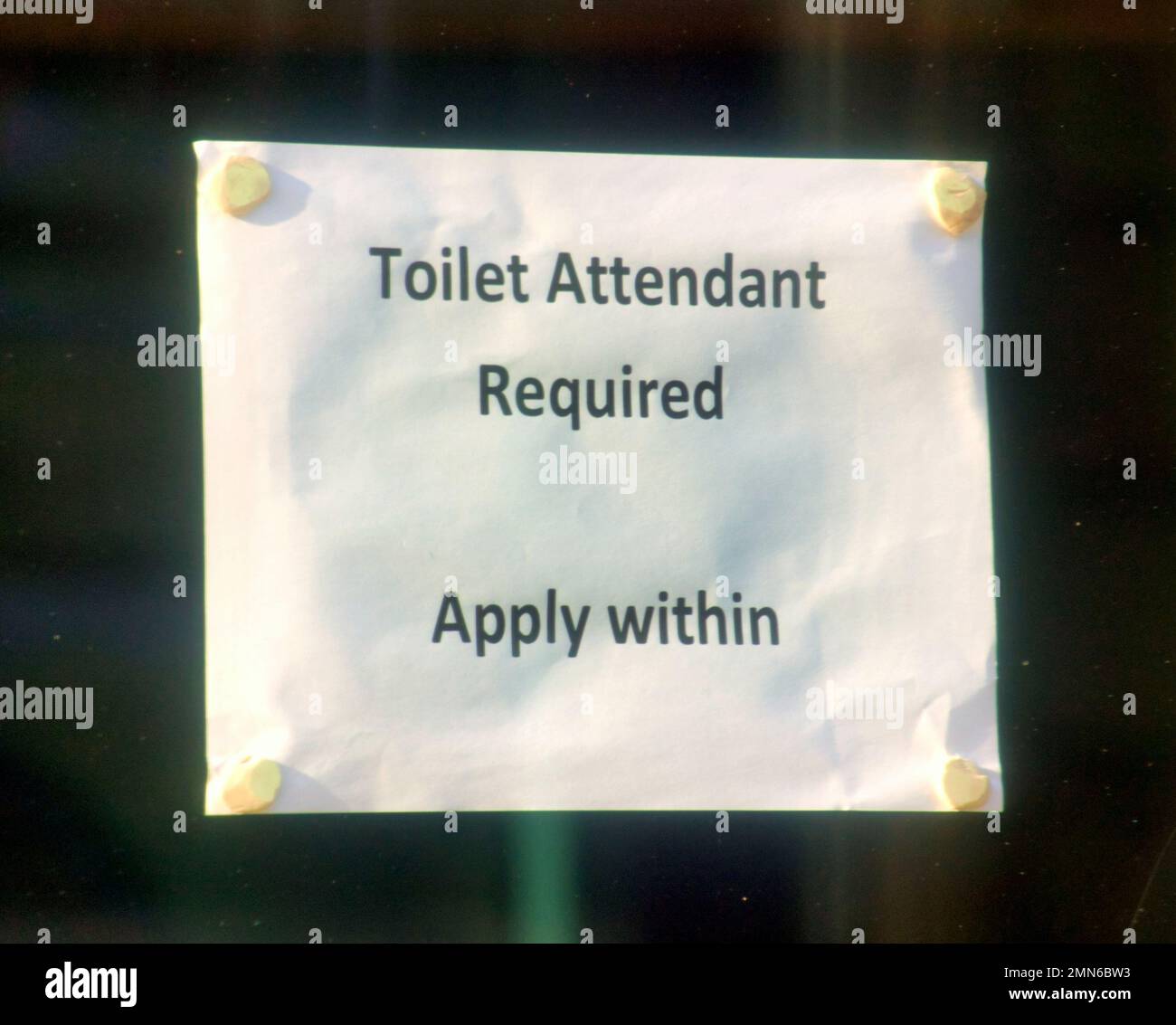 toilet attendant required apply within sign in shop window Stock Photo