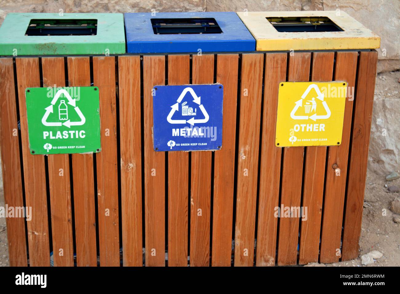 A wooden trash bin for different garbage with an inscription in English (Plastic, metal and