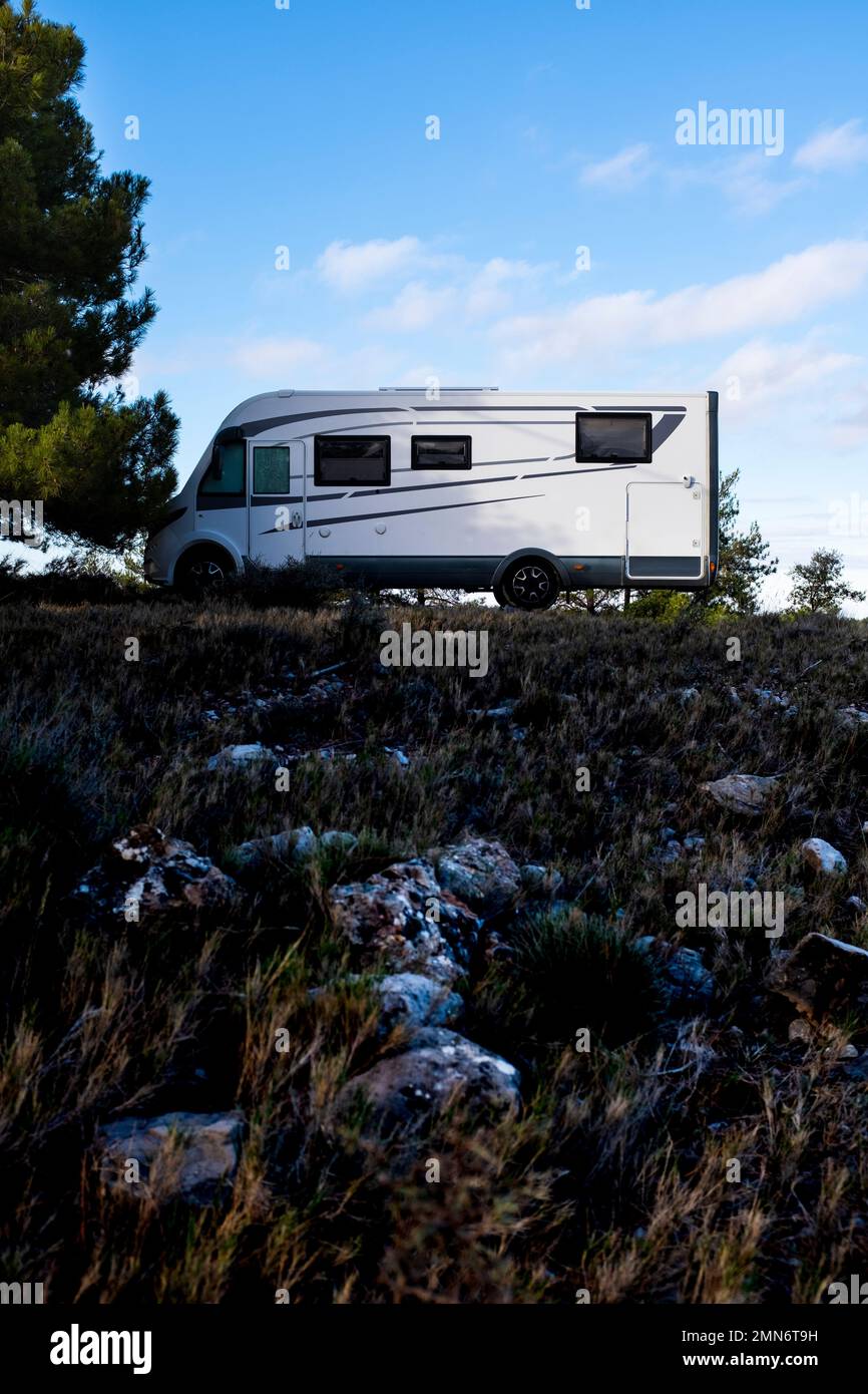 Modern camper van motor home in natural parking park with blue sky in background. Concept, of freedom and alternative wild vacation. Journey and holid Stock Photo
