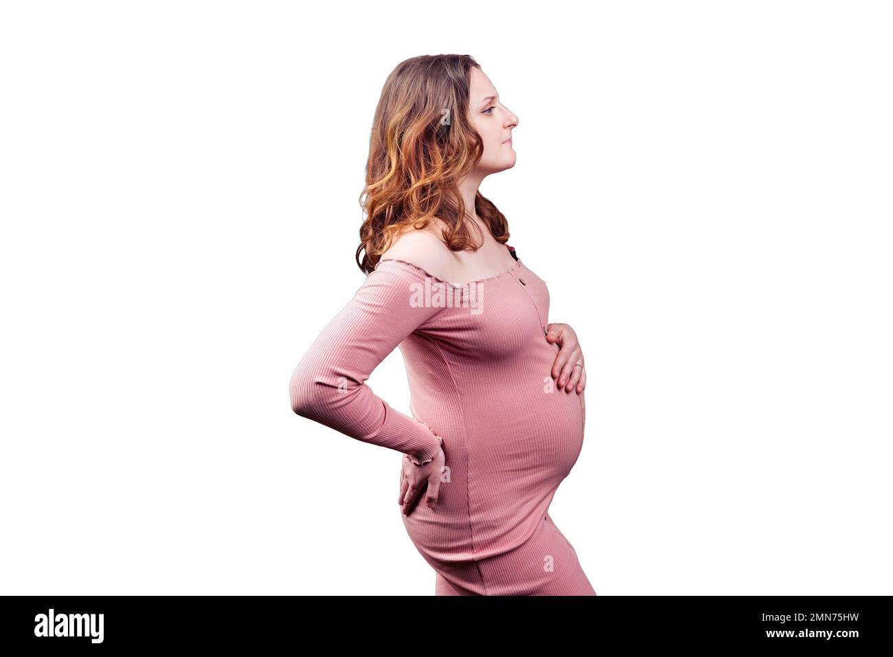Portrait of an adult pregnant woman in profile, isolated on a white background. 35 year old woman with long curly hair in pink bodycon dress Stock Photo