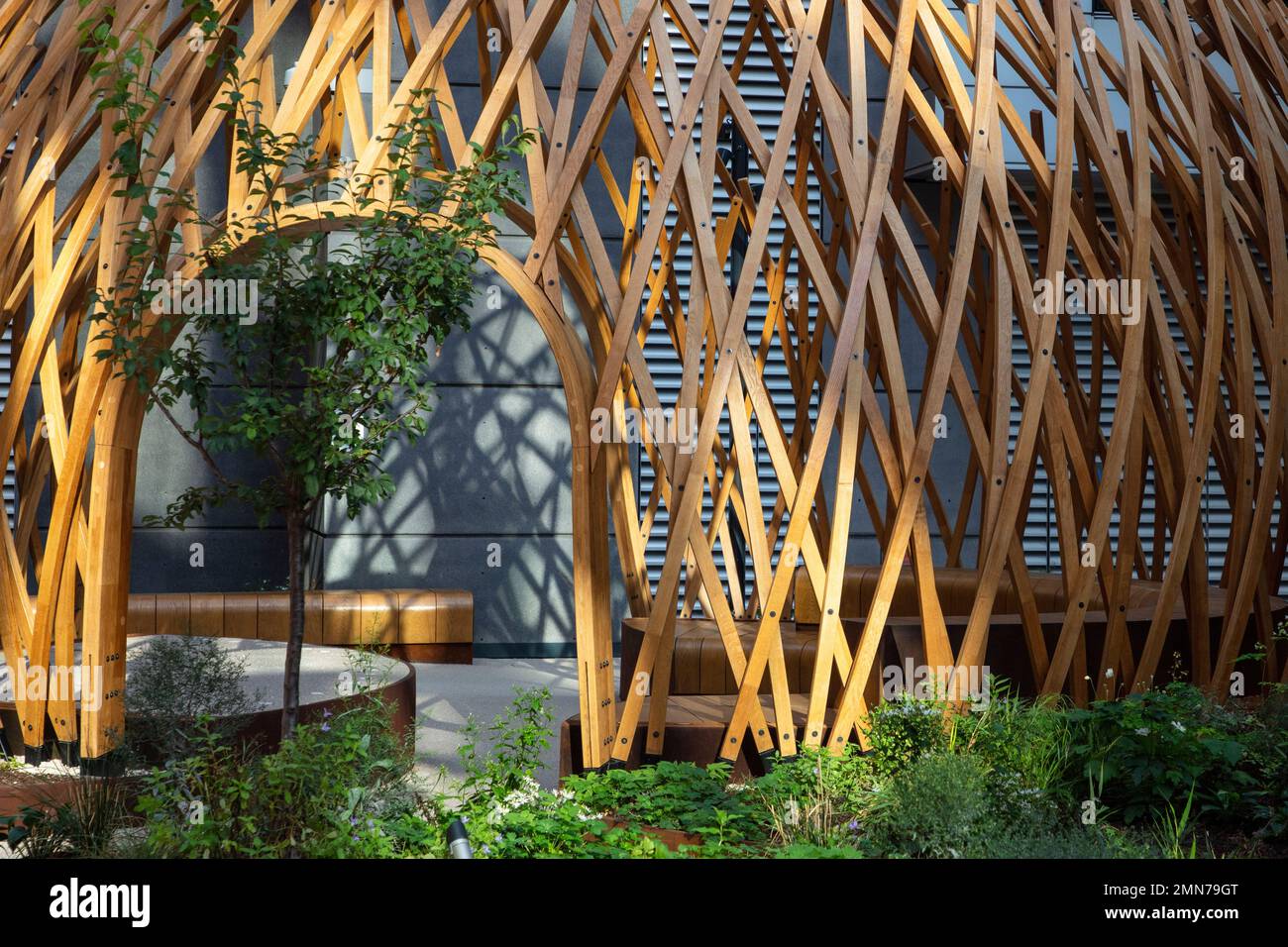 Curved wooden structure with strong shadows. Osnaburgh Pavilion at Regents Place, London, United