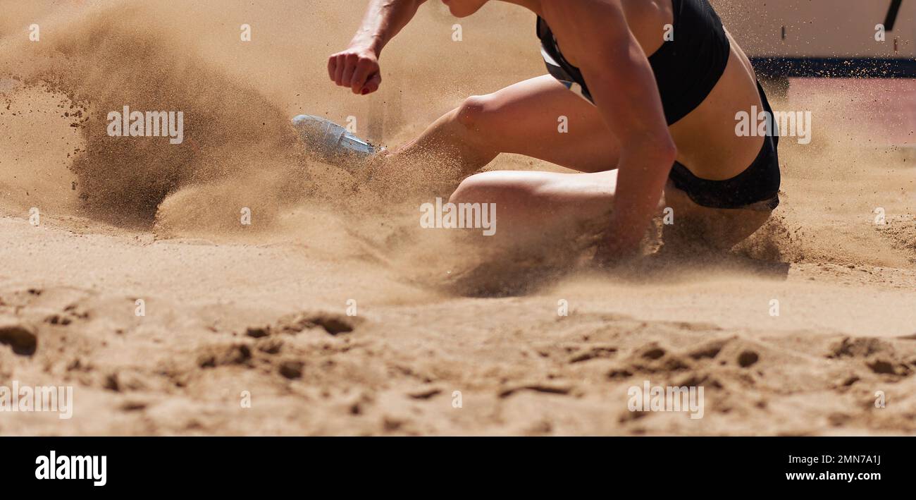 Female athlete long jump landing sand spray Stock Photo Alamy