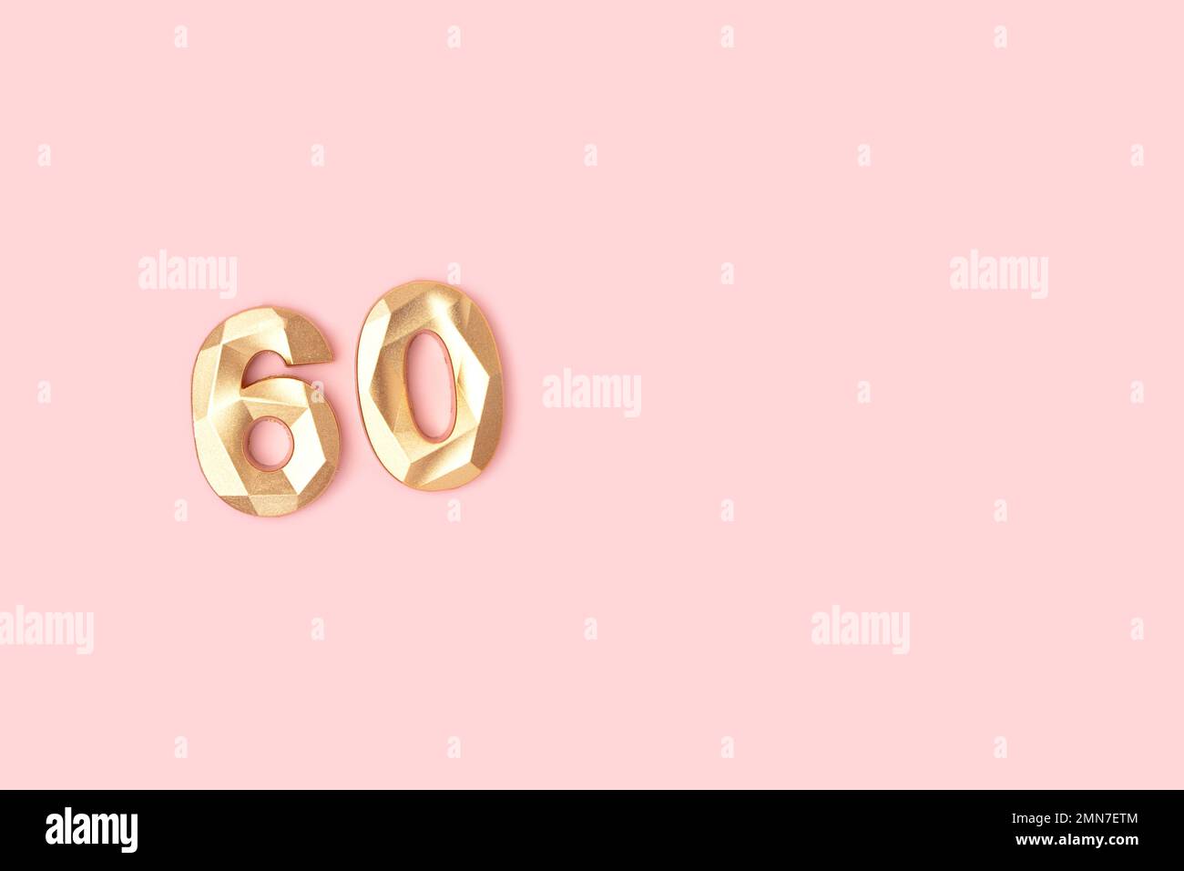 Golden number 60 on a pink background. Minimal composition. Stock Photo