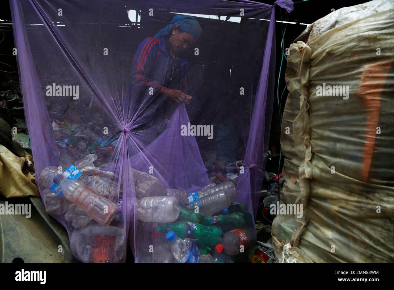 A worker segregates plastic waste for recycling at a junkyard in