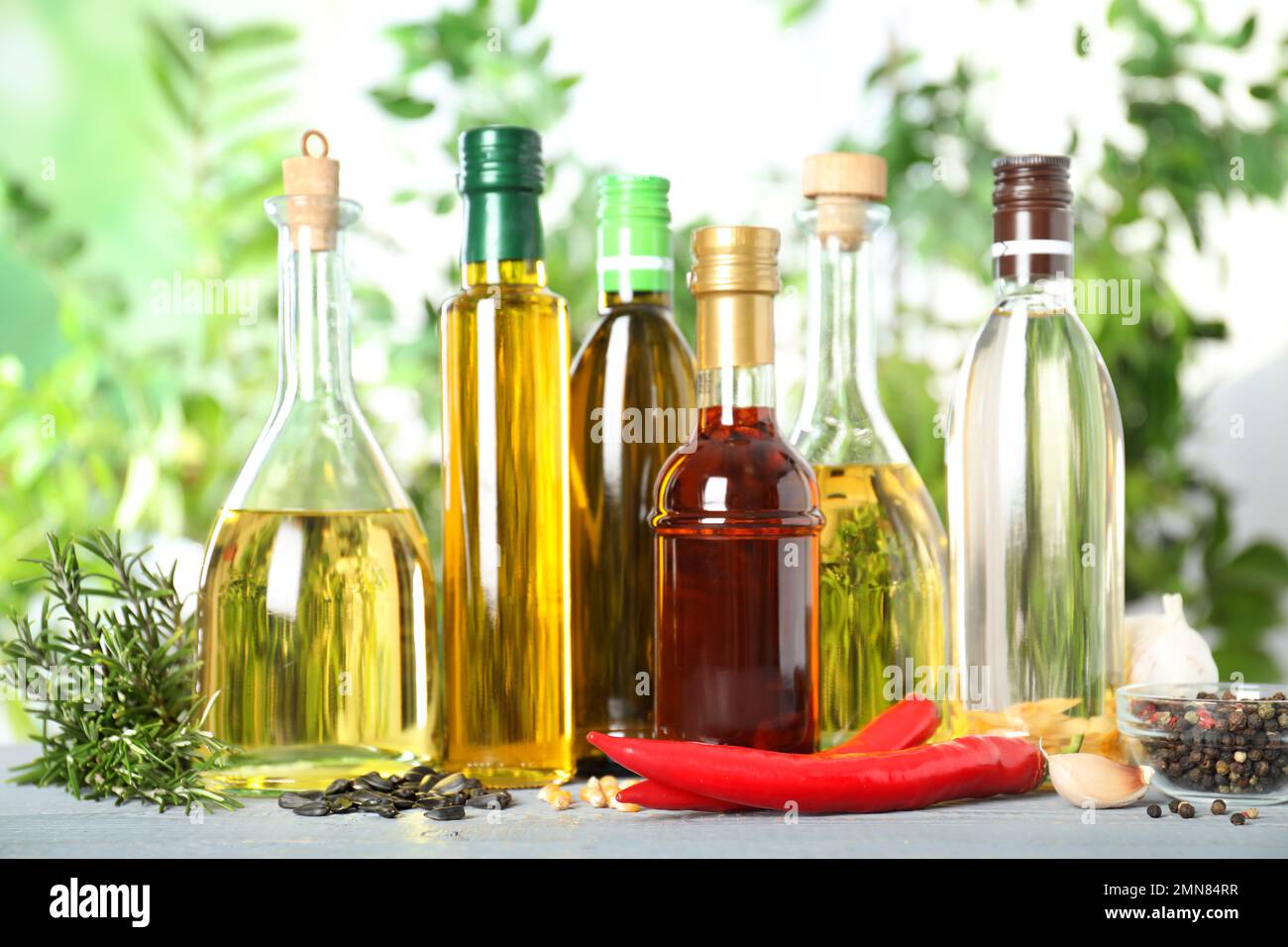 Different sorts of cooking oil in bottles and ingredients on white