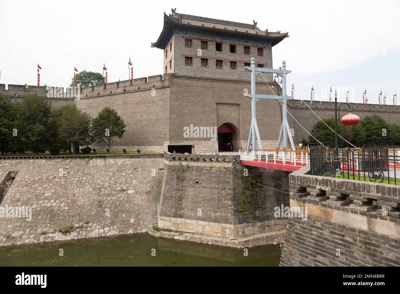 Heavily restored section of the fortifications of Xi'an, also known as Xian City Wall, complete with a gatehouse watch tower. A 'moat' with water, crossed by a bridge drawbridge further protects the ancient city. China. PRC. Stock Photo