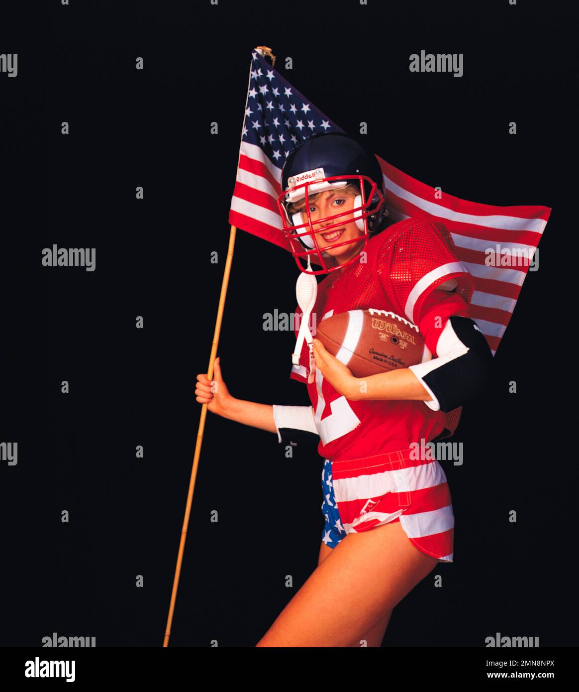 Young woman American football player carrying USA flag. Stock Photo