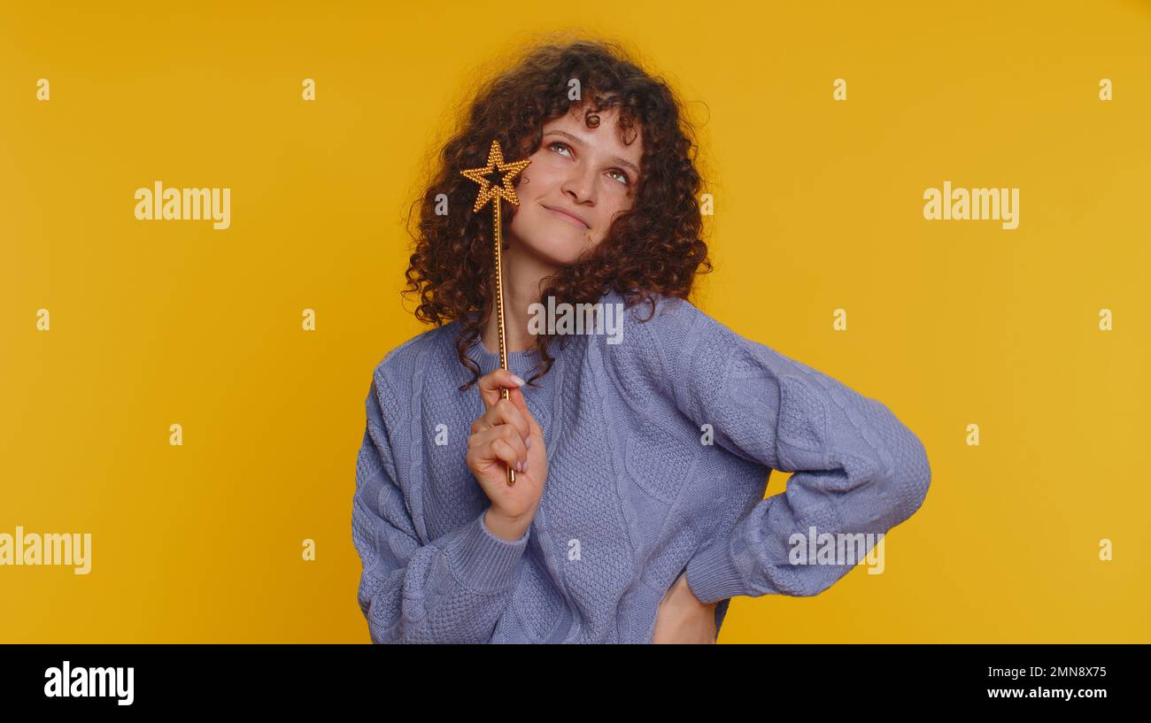 Magician witch woman gesturing with magic wand fairy stick, making wish come true, casting magician spell, advertising holidays sale discount. Young teen girl isolated on yellow studio background Stock Photo