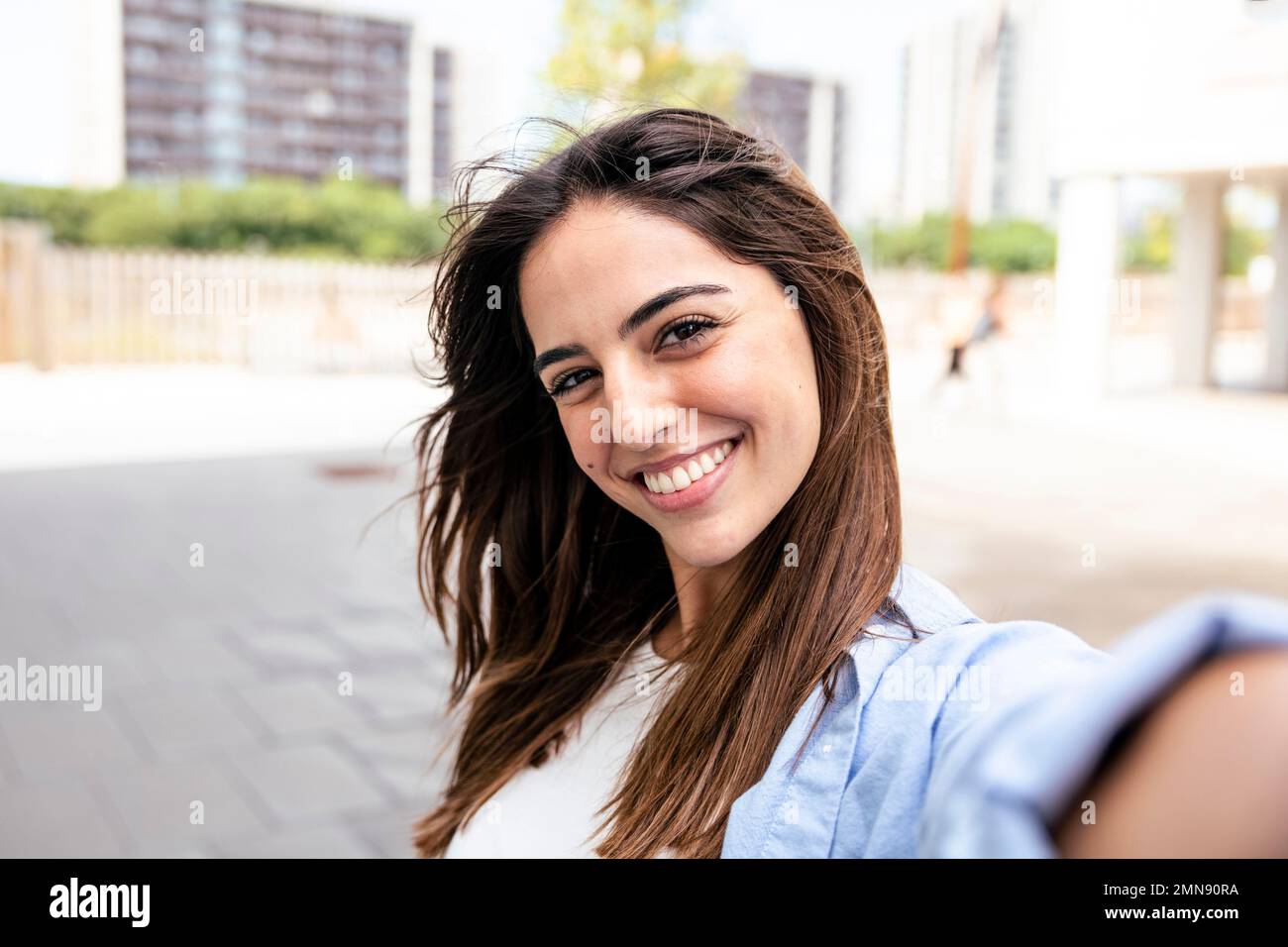 Selfie-portrait of pretty girl in the city. Portarit of happy young beautiful woman doing a selfie photo on the camera.  Stock Photo
