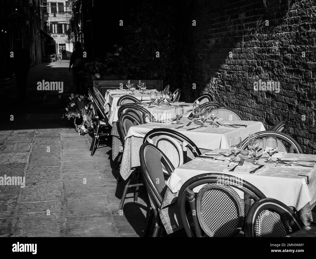 Black and white photo of restaurant tables set outdoors in the street. Stock Photo