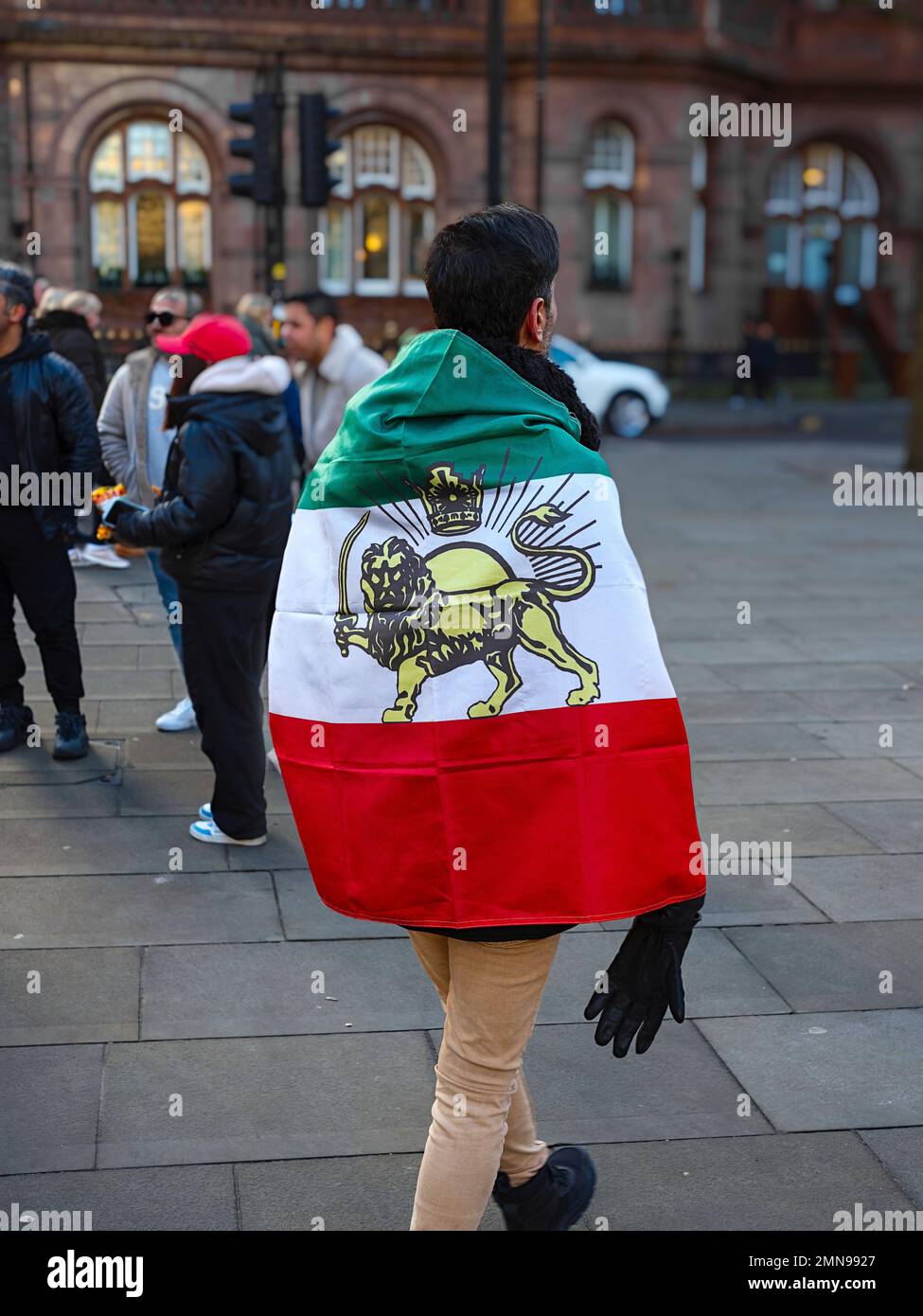 Manchester UK Jan 2023 Man wrapped with Iranian flag at freedom for Iran protest march Stock Photo