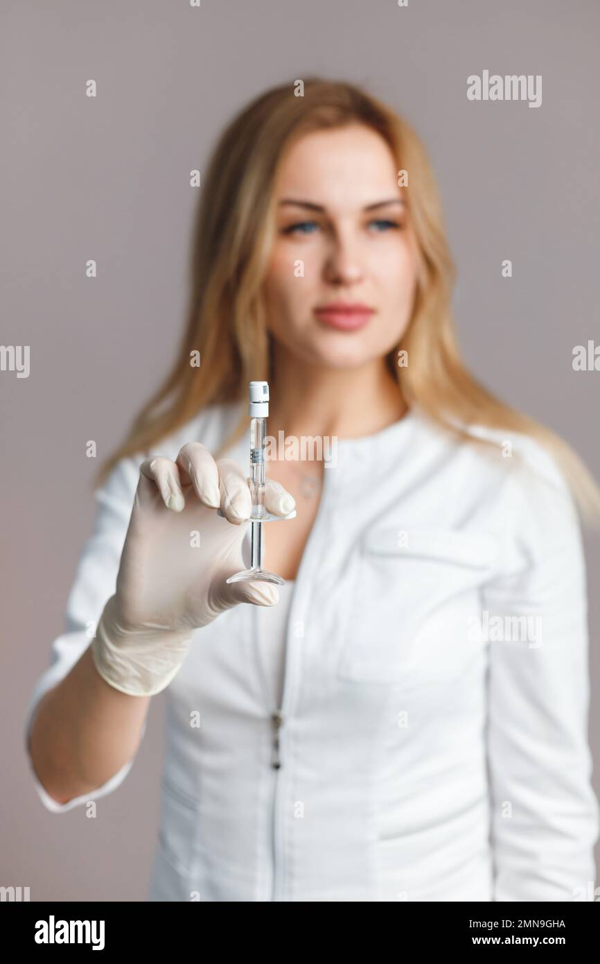 Cosmetologist wearing doctor robe in medical glove holds syringe for injection with collagen hyaluronic filler Stock Photo