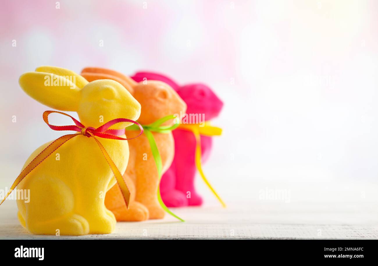 Easter decoration with Easter colorful rabbits on white wooden table. Easter concept with copy space. Stock Photo