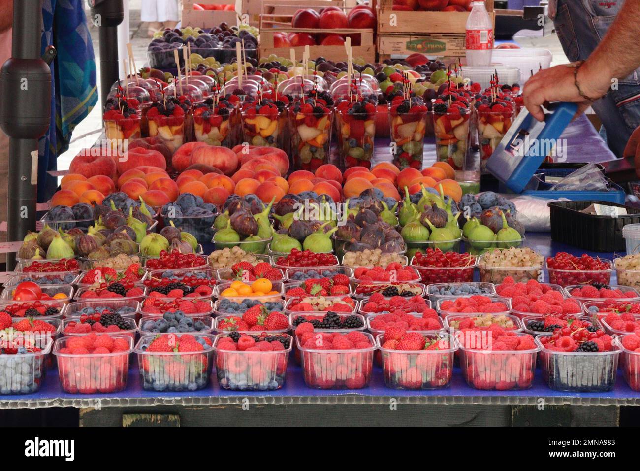 A mouthwatering selection of fruit displayed by a market trader in Dubrovnik old town. He adds to his cash box following another successful sale. Stock Photo