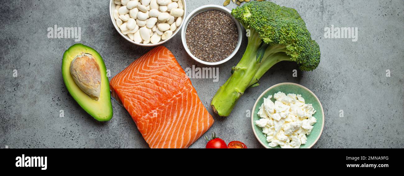 Selection of healthy food products if a person have diabetes: salmon fish, broccoli, avocado, beans, vegetables, seeds on grey background from above Stock Photo
