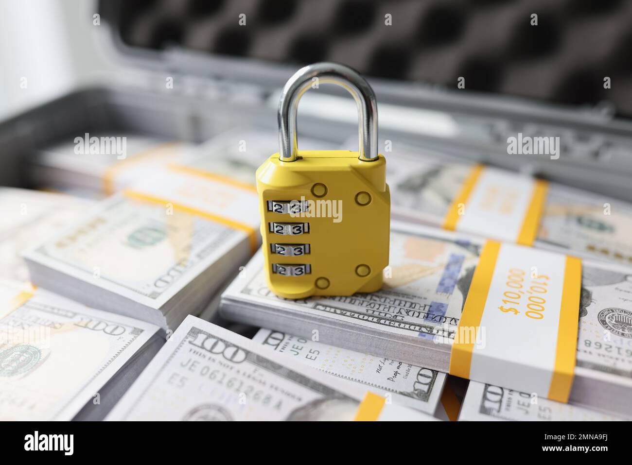 Yellow padlock with combination on many stacks of US dollars close-up. Stock Photo