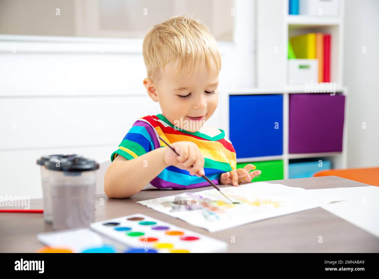 Cute boy drawing picture by using watercolors indoors. Stock Photo