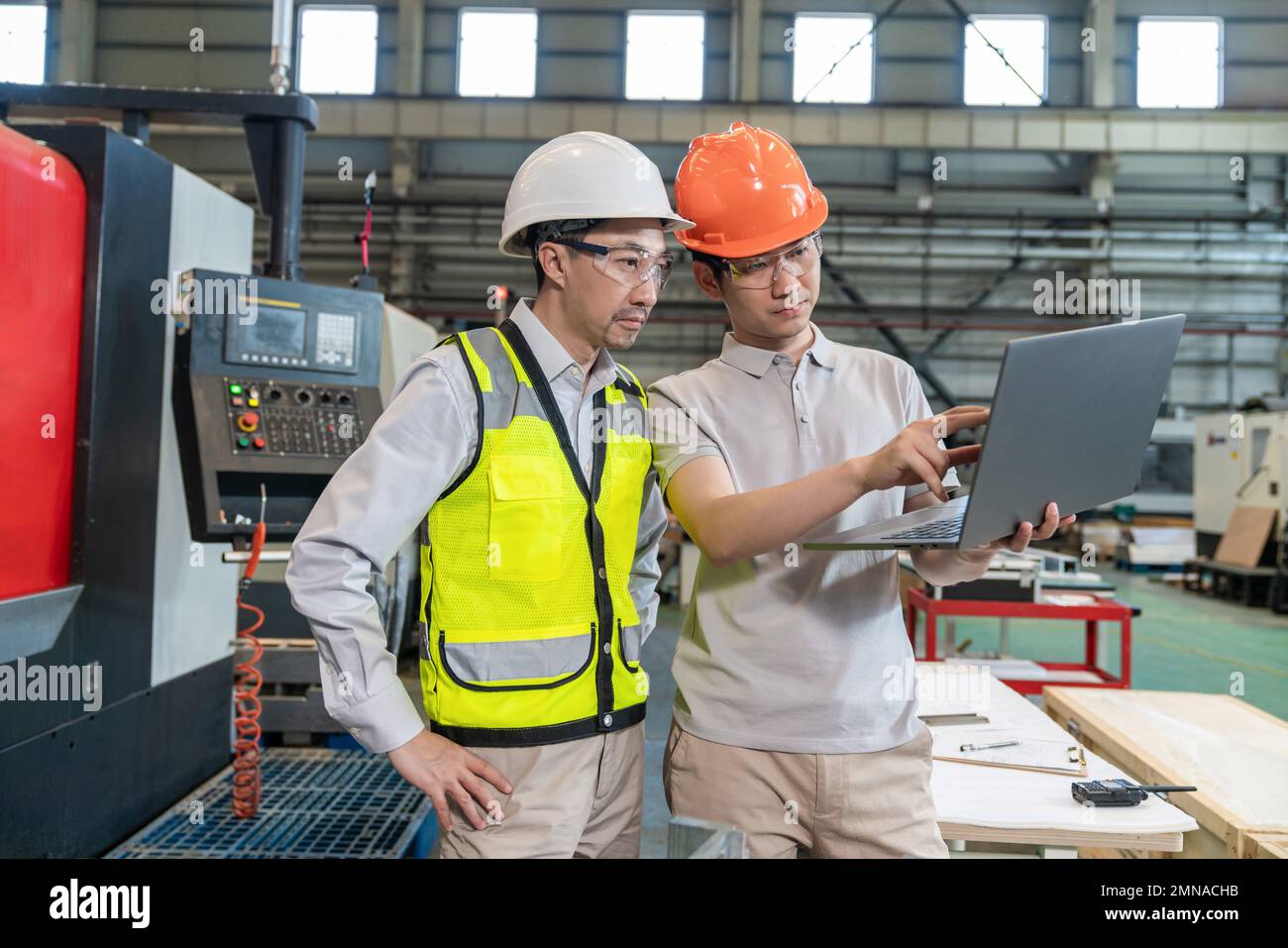 Two engineers wear protective overalls wearing helmets do measurement