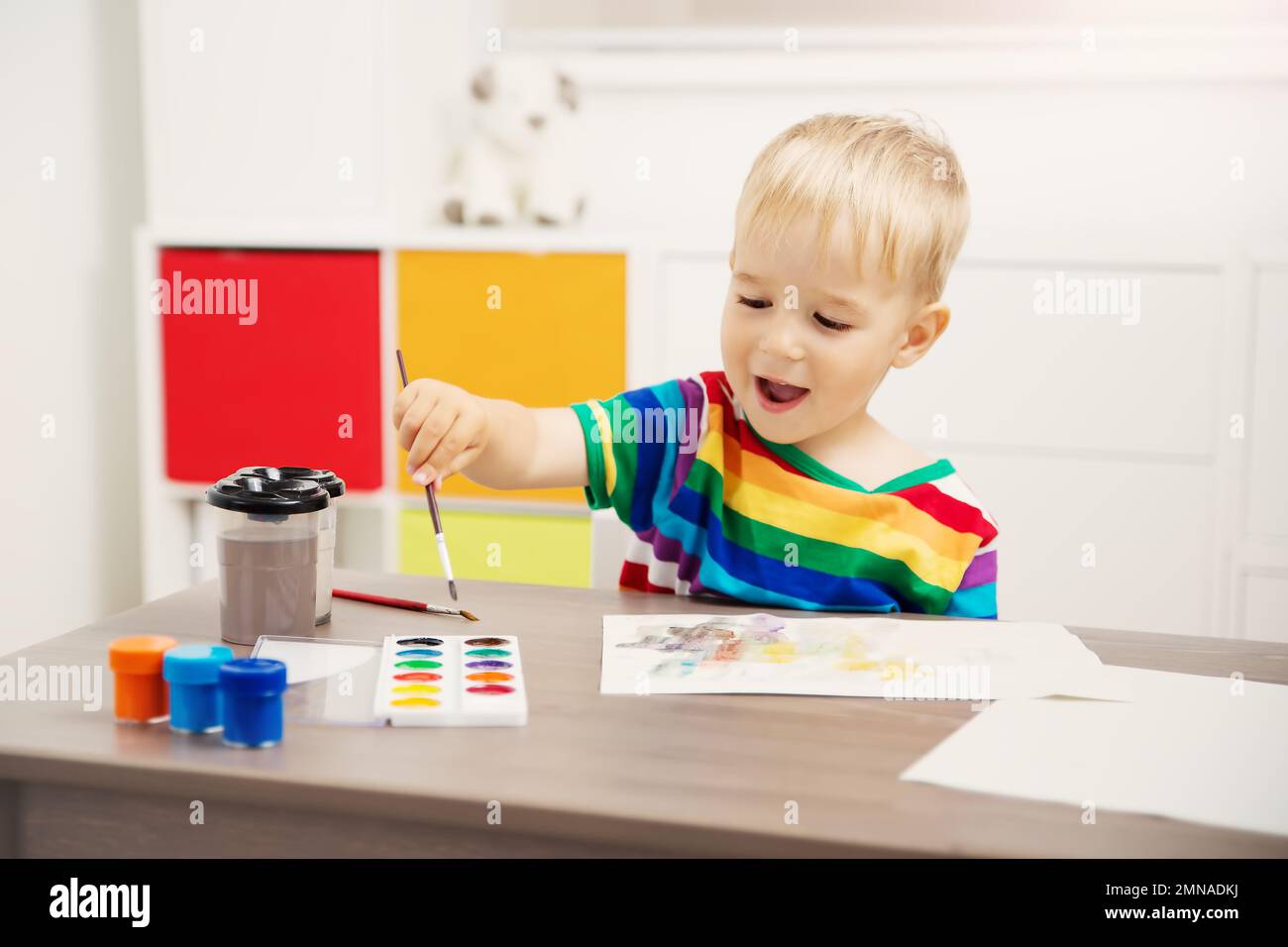 Cute boy drawing picture by using watercolors and couache indoors. Stock Photo