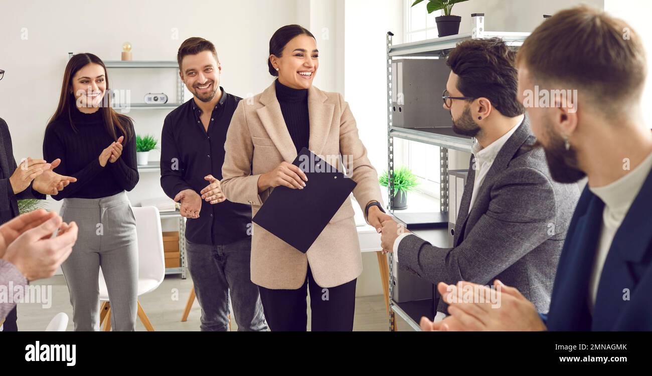 Team of people congratulating woman on her promotion and showing recognition for her work Stock Photo